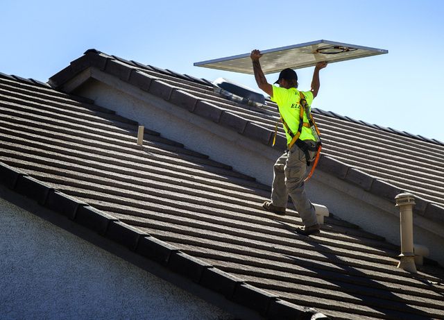 Jacy Sparkman with  Robco Electric carries a solar panel at a home in northwest Las Vegas on Friday March 13, 2015. The company estimated that the 17 panel  4.675 KWDC solar project will save this ...