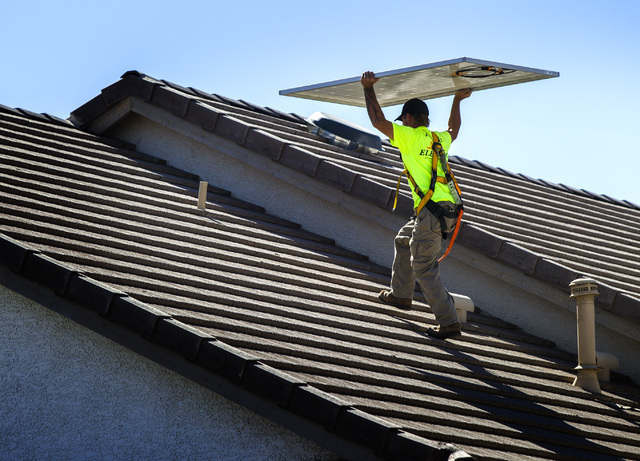 Jacy Sparkman with Robco Electric carries a solar panel at a home in northwest Las Vegas on Friday March 13, 2015. The company estimated that the 17 panel 4.675 KWDC solar project will save this ...