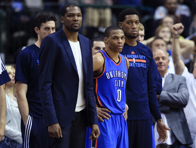 Mar 16, 2015; Dallas, TX, USA; Oklahoma City Thunder forward Kevin Durant (left) and guard Russell Westbrook (0) and forward Perry Jones (right) react on the bench during the second half against t ...