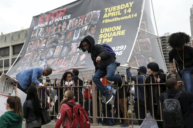 Demonstrators climb over a fence during a protest against police brutality against minorities in New York, April 14, 2015. (REUTERS/Shannon Stapleton)