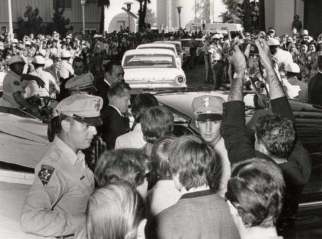 Members of the British rock 'n' roll band The Beatles are flanked by Las Vegas police officers as the are escorted to a waiting limousine at the Sahara in Las Vegas, Aug. 20, 1964, as screaming fa ...