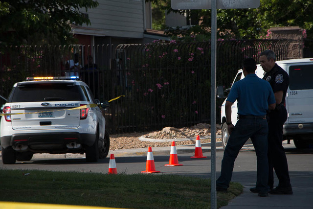 North Las Vegas police spokesman officer Aaron Patty talks to a uniformed officer after a double shooting near Cartier Avenue and Donna Street on Saturday, April 11, 2015. One person was killed an ...