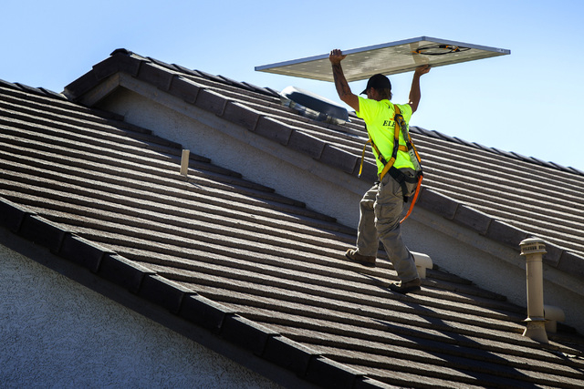Jacy Sparkman with Robco Electric carries a solar panel at a home in northwest Las Vegas on Friday March 13, 2015. The company estimated that the 17 panel  4.675 KWDC solar project will save this  ...