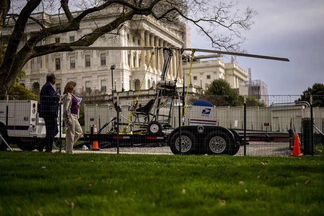 People walk past a gyro copter that was flown onto the grounds of the U.S. Capitol before it was towed from the west front lawn in Washington April 15, 2015. A bomb squad has determined there was  ...