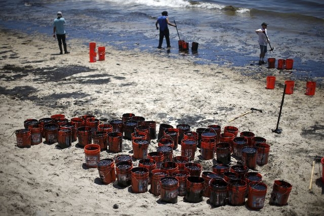Volunteers fill buckets with oil from an oil slick along the coast of Refugio State Beach in Goleta, California, United States, May 20, 2015. An oil pipeline that burst along the California coast, ...
