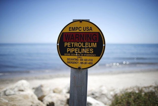 A sign warns of petroleum pipelines next to an oil slick along the coast of Refugio State Beach in Goleta, California, May 20, 2015. An oil pipeline that burst along the California coast, fouling ...