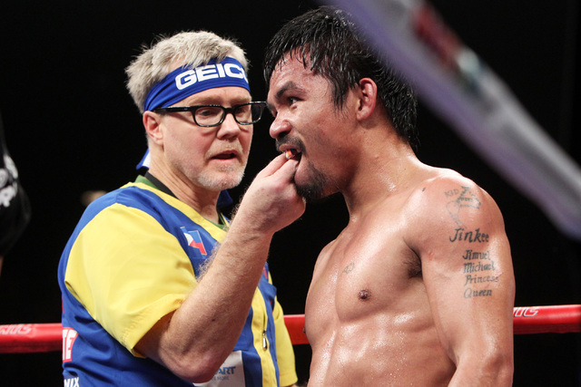 Trainer Freddy Roach removes Manny Pacquiao's mouth guard between round of his welterweight unification boxing match against Floyd Mayweather Jr. at the MGM Grand Garden Arena in Las Vegas on Satu ...