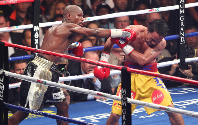 Floyd Mayweather Jr., left, throws a punch at Manny Pacquiao in their welterweight unification boxing match at the MGM Grand Garden Arena in Las Vegas on Saturday, May 2, 2015. (Chase Stevens/Las  ...