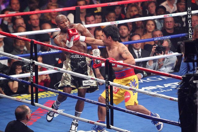 Manny Pacquiao, right, throws a punch at Floyd Mayweather in their welterweight unification boxing match at the MGM Grand Garden Arena in Las Vegas on Saturday, May 2, 2015. (Chase Stevens/Las Veg ...