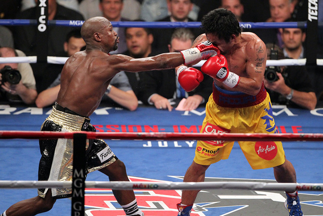 Floyd Mayweather Jr., left, lands a blow to Manny Pacquiao in the sixth round of their welterweight unification boxing match at the MGM Grand Garden Arena in Las Vegas on Saturday, May 2, 2015. (E ...
