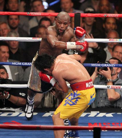 Floyd Mayweather Jr., top, goes after Manny Pacquiao in the sixth round of their welterweight unification boxing match at the MGM Grand Garden Arena in Las Vegas on Saturday, May 2, 2015. (Erik Ve ...