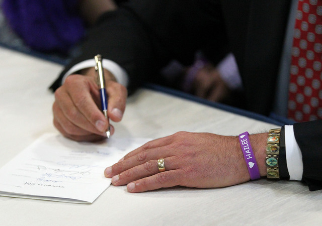 Wearing his wristband showing support for White Middle School student Hailee Lamberth who committed suicide, Nevada Gov. Brian Sandoval signs an anti-bullying bill into law at Carson Middle School ...