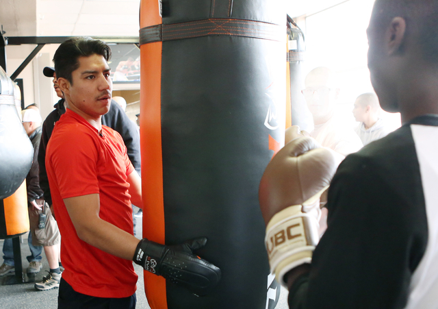 Boxer Jessie Vargas, left, gives a lesson on how to use a heavy punching bag to a young boxer at the Spring Mountain Youth Camp Wednesday, April 22, 2015.  Professional boxers and boxing referees  ...