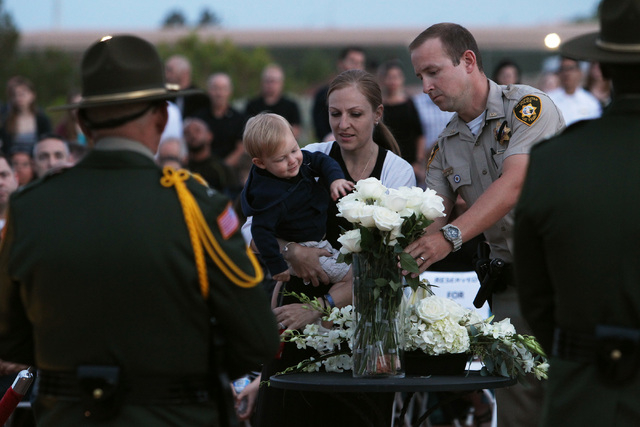Logan Soldo reaches for a flower after his mother Andrea Soldo placed it in a vase during a memorial Thursday, May 21, 2015, for Metro officers Alyn Beck and Igor Soldo who were killed in the line ...