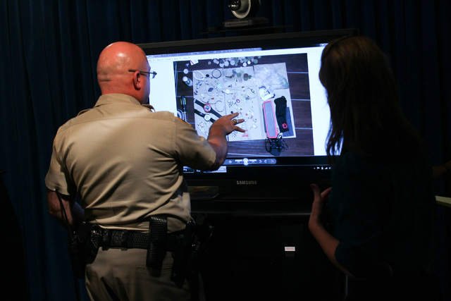 Las Vegas police officials look over images before Undersheriff Kevin McMahill addresses news media about an officer-involved shooting that took place April 29, at Las Vegas police headquarters on ...