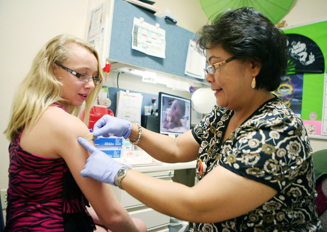 Twelve-year-old Skylar Roberts, left, receives a bandage from registered nurse Detet Gonzales after a vaccination shot at Southern Nevada Health District, 560 N. Nellis Blvd., in Las Vegas, Thursd ...