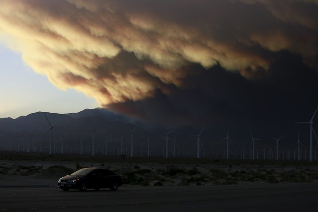 A smoke plume from the Lake Fire in the San Bernardino National Forest is seen at sunset, rising over a windmill farm from Palm Springs, California June 18, 2015. Some 500 firefighters backed by ...