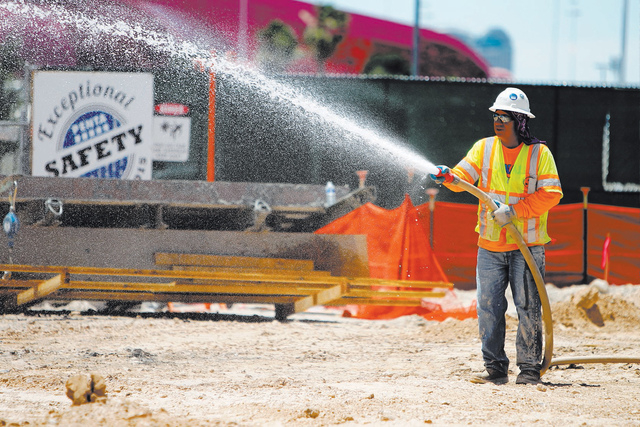 Construction laborer Saul Valdez hose down the dirt following a presentation hosted by the PENTA Building Group on the safety hazards heat brings at the Lucky Dragon casino-hotel construction site ...