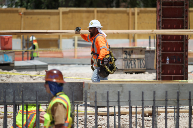 A contraction worker moves boards following a presentation hosted by the PENTA Building Group on the safety hazards heat brings at the Lucky Dragon casino-hotel construction site in Las Vegas on M ...