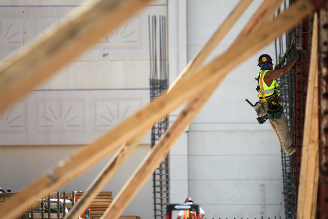 A contraction climbs a steel building column following a presentation hosted by the PENTA Building Group on the safety hazards heat brings at the Lucky Dragon casino-hotel construction site in Las ...