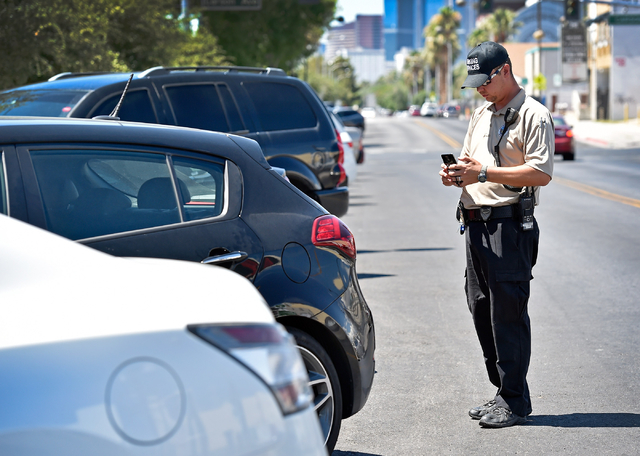 Parking enforcement officer Joshua Kuykendall writes a warning citation for no current registration sticker visible on a vehicle along 7th Street in downtown Las Vegas on Friday, June 12, 2015. Ku ...
