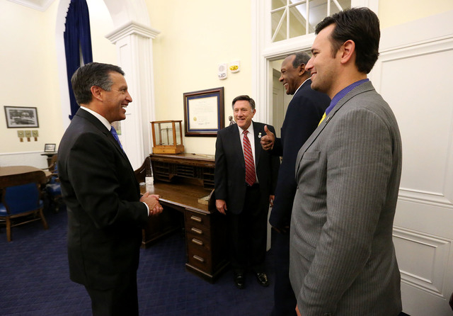 Nevada Gov. Brian Sandoval, left, congratulates Assemblymen PK O'Neill, Harvey Munford and Stephen Silberkraus after the end of session at the Legislative Building in Carson City, Nev., on Tuesday ...