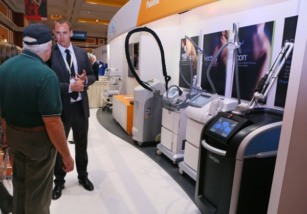 Brad Hallock, right, speaks to attendee Gary Butka, of Brownwood, Texas, at the Cynosure booth during THE Aesthetic Show at Wynn hotel-casino. Aesthetic laser systems can be seen at right. (Ronda  ...