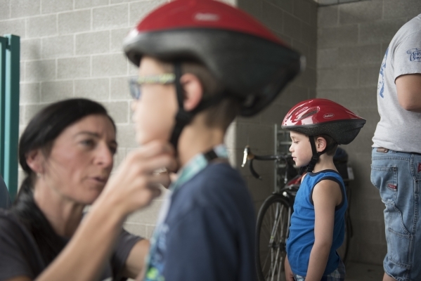 Shannon Gaffney fits a helmet on David Freedman, 6, as Matthew Freedman, 6, looks on at the bicycle helmet giveaway at Black Mountain Recreation Center in Henderson, Saturday, July 18, 2015. (Jaso ...