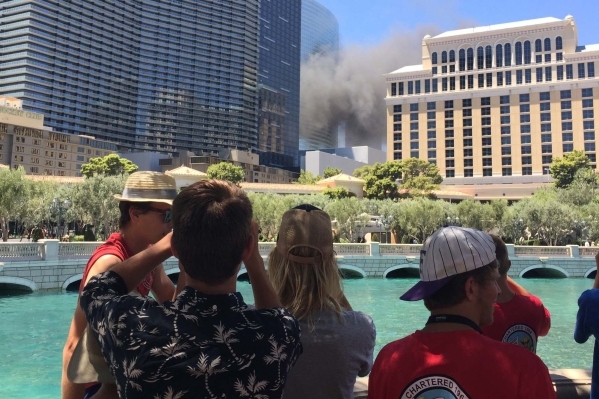 Tourists near the Bellagio watch as smoke rises near the Cosmopolitan hotel-casino on the Strip in Las Vegas on Saturday, July 25, 2015. (Joshua Dahl/Las Vegas Review-Journal)