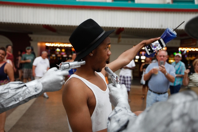 Chris Johnsun takes a selfie with the Silver and Gold Statues on Fremont Street on Wednesday, July 29 2015. The city hopes to set up zones for street performers on Fremont Street.