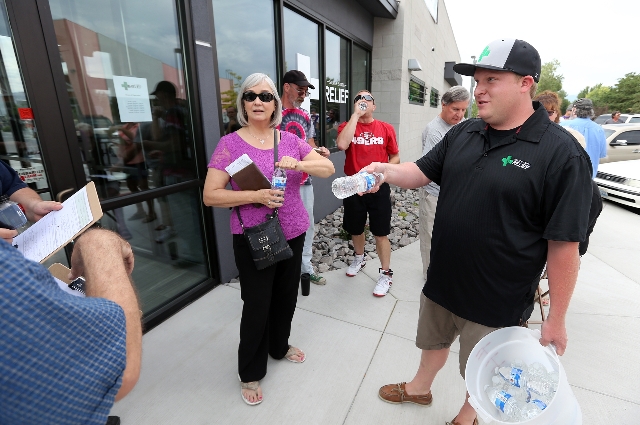 Manager Garrett Newman passes out water bottles to people waiting for the opening of Silver State Relief in Sparks on Friday, July 31, 2015. More than 50 people with state-authorized medical cards ...