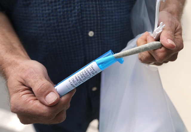 A customer who declined to give his name shows a joint to reporters after filling a prescription at Silver State Relief, the first medical marijuana dispensary in Sparks on Friday morning, July 31 ...