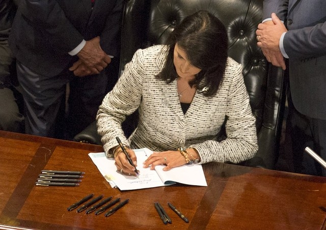 South Carolina Gov. Nikki Haley signs legislation on Thursday, July 9, 2015, in Columbia, South Carolina, permanently removing the Confederate battle flag from the state capitol grounds, following ...