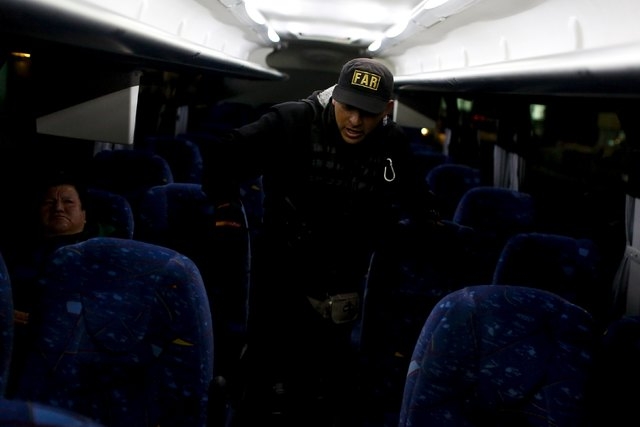 A policeman inspects a passenger bus at a checkpoint outside the Altiplano Federal Penitentiary, after drug lord Joaquin 'El Chapo' Guzman escaped, in Almoloya de Juarez, on the outskirts of Mexic ...