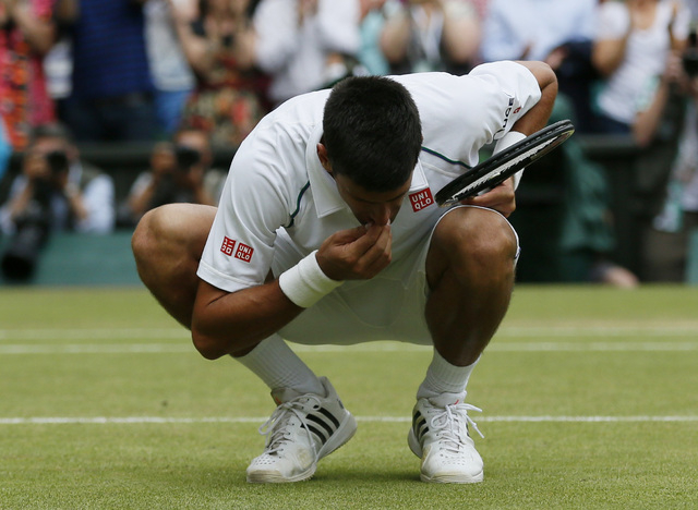 Novak Djokovic of Serbia eats some grass off Centre Court after winning his Men's Singles Final match against Roger Federer of Switzerland at the Wimbledon Tennis Championships in London, July 12, ...