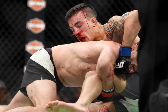 Blood pours from the nose of Thomas Almeida as he grapples with Brad Pickettduring their fight at UFC 189 Saturday, July 11, 2015 at the MGM Grand Garden Arena in Las Vegas, Nevada. Almeida won wi ...