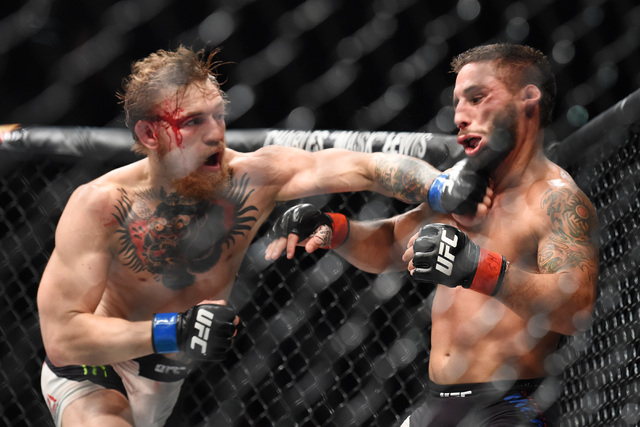 Conor McGregor sends Chad Mendes to the mat with a left to win by TKO in the second round of their featherweight title fight at UFC 189 Saturday, July 11, 2015 at the MGM Grand Garden Arena in Las ...