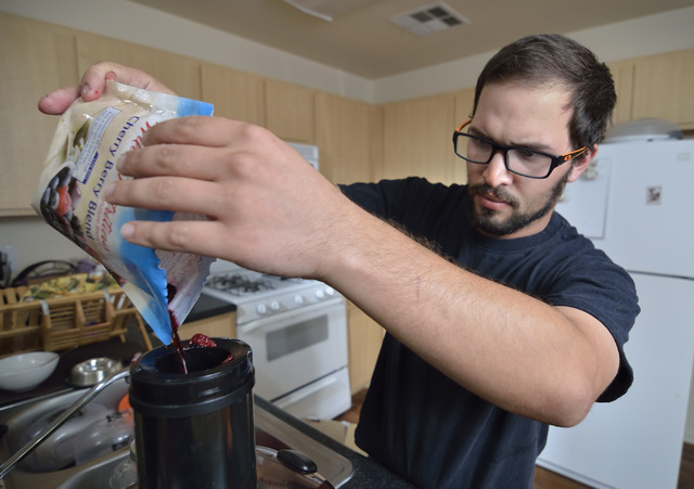 John Brownie adds frozen berries to a juicer at his home in Las Vegas on Tuesday, June 30, 2015. Dietary changes such as cutting dairy products have helped him get a case of irritable bowel syndro ...