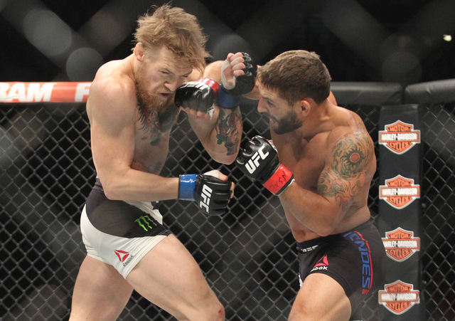 Conor McGregor, left, trades jabs with Chad Mendes during their interim featherweight title bout at UFC 189 at the MGM Grand Garden Arena Saturday, July 11, 2015, in Las Vegas. McGregor won by kno ...