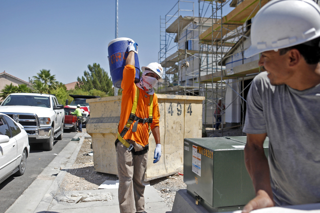 Carlos Salseda of Adaven Homes, left, carries a jug with several gallons of water on it to his construction site on Wednesday, July 1, 2015, in North Las Vegas. This past June was the hottest on r ...