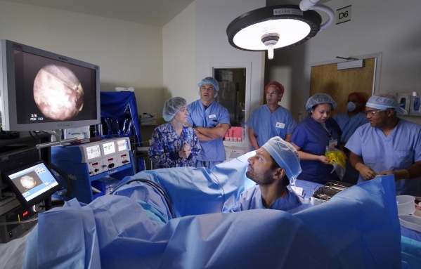 Dr. Jayram Krishnan, foreground, is shown during a procedure to remove cancer tissue from a patient‘s bladder at Sunrise Hospital and Medical Center in July. Part of the procedure involved u ...
