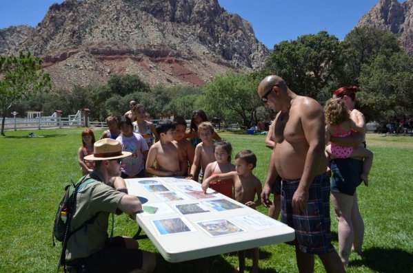 Spring Mountain Ranch State Park interpreter David Low, left, quizzes children on water conservation information as they wait in line for their turn on a horizontal water slide at Water on the Mea ...