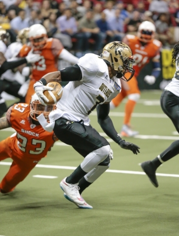 Las Vegas Outlaws Ray Little (7) looks for an opening through through other players, while being grabbed by Spokane Shocks player Jeff Richards (23) 
 during a football game between the Las Vegas  ...