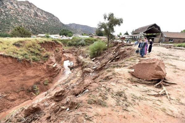 Residents look down an estimated 50-foot deep gorge that was created after a flash flood in Hildale, Utah September 15, 2015. At least eight people were killed near Utah‘s border with Arizon ...
