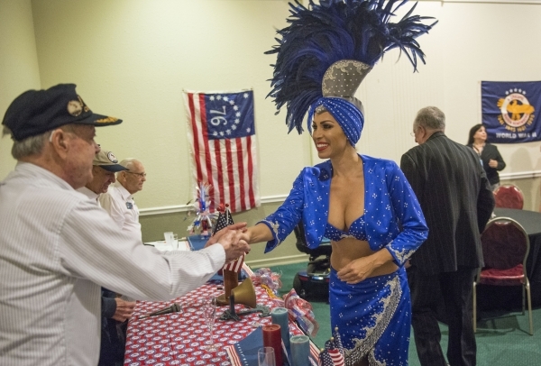 Rudy Moraga, a survivor of the USS Bismarck Sea, shakes hands with showgirl Jennifer Johnson during a reunion of the survivors of the USS Bismarck Sea, at the Plaza Hotel in Las Vegas on Tuesday,  ...