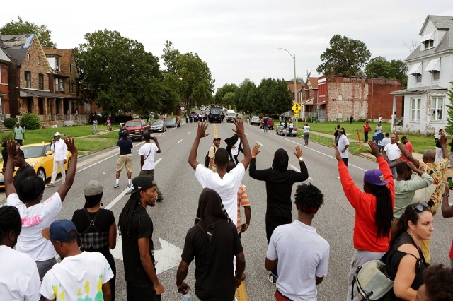 Protestors hold their hands up as police approach them on Page Ave. after a shooting incident in St. Louis, Missouri August 19, 2015. Police fatally shot a black man they say pointed a gun at them ...