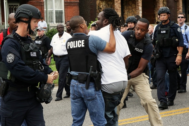 Police arrest a protester that was in the middle of the street after a shooting incident in St. Louis, Missouri August 19, 2015. Police fatally shot a black man they say pointed a gun at them, dra ...