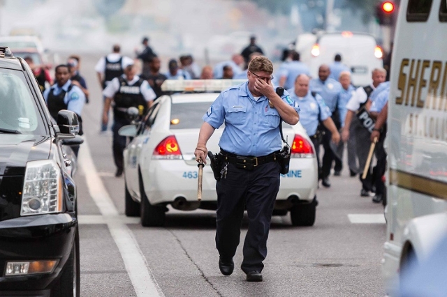 A policeman rubs his eyes after police attempted to disperse a crowd using what appeared to be teargas after a shooting incident in St. Louis, Missouri August 19, 2015. Police fatally shot a black ...