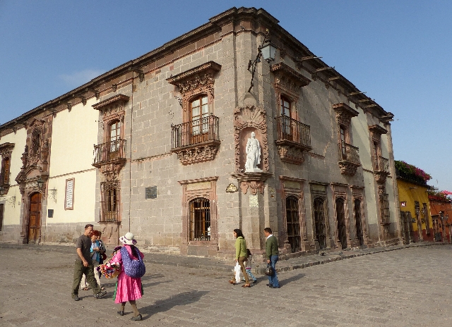 Tourists and a handicrafts seller walk past the Allende House Museum, which faces the central square of San Miguel de Allende, Mexico, August 3, 2015. REUTERS/Walker Simon