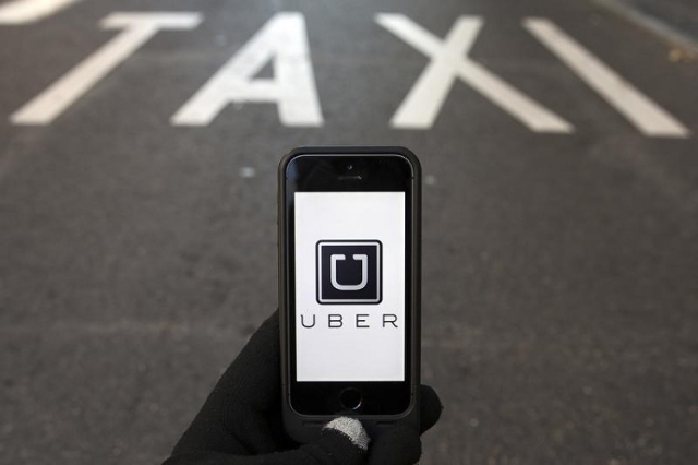 The logo of car-sharing service app Uber on a smartphone over a reserved lane for taxis in a street is seen in this photo illustration taken in Madrid on December 10, 2014. (Reuters/Sergio Perez)